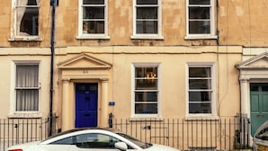 Un edificio a più piani con una porta blu, diverse finestre e un'auto parcheggiata davanti.