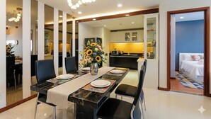 A modern dining area with a marble table, black chairs, and a vase of sunflowers. - BMC BUILDING (Ho Chi Minh City)