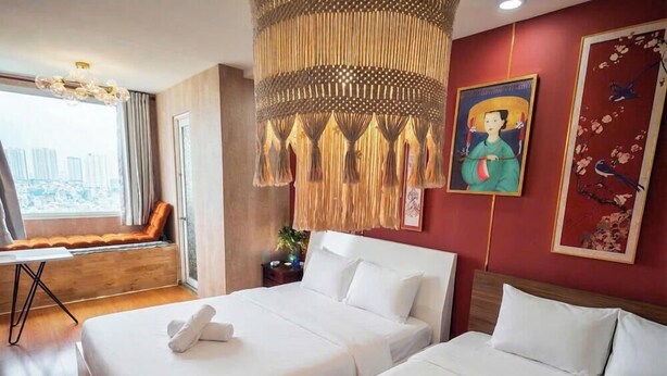 A hotel room with two beds, a large window with a view, a hanging decorative piece, and artwork on the walls. - BMC BUILDING (Ho Chi Minh City)