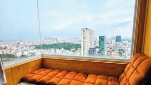 A corner room with a view of a cityscape, a cushioned bench, and a window. - BMC BUILDING (Ho Chi Minh City)