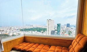 A corner room with a view of a cityscape, a cushioned bench, and a window. - BMC BUILDING (thanh pho Ho Chi Minh)