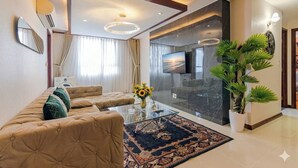 A modern living room with a sofa, a coffee table, a TV, and a large potted plant. - BMC BUILDING (Ho Chi Minh City)