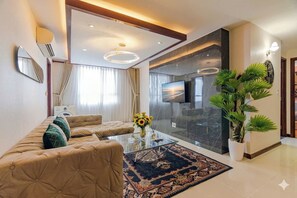 A modern living room with a sofa, a coffee table, a TV, and a large potted plant. - BMC BUILDING (thanh pho Ho Chi Minh)