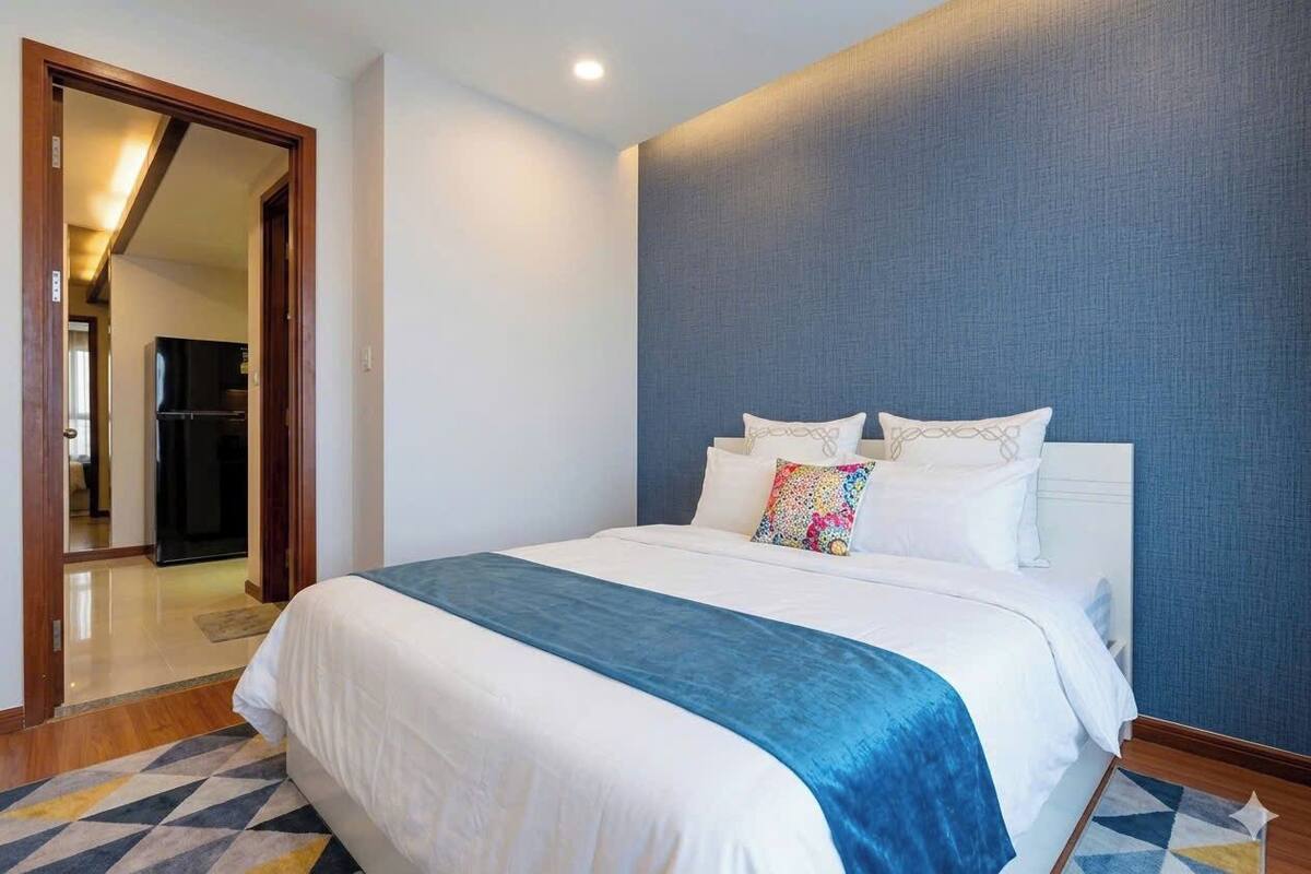 Ein Hotelzimmer mit einem Bett, einer blauen Wand und einer Tür zu einer Küchenzeile.