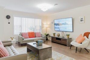 A living room with a sofa, armchair, coffee table, TV, and decorative items. - Sky-View | Modern 2BR Retreat + Balcony (490861) (Sydney)