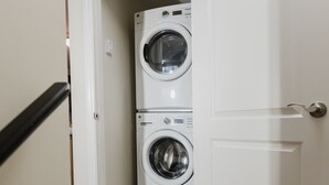 A laundry room with two stacked front-loading washing machines. - Garden Suite | Modern 2BR with Private Yard (Sydney)