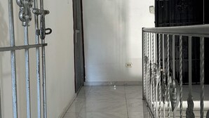 Un passadís amb barana metàl·lica, una porta i una reixa negra.