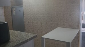 Una cuina petita amb taulella de granat, una taula blanca i parets amb motius.