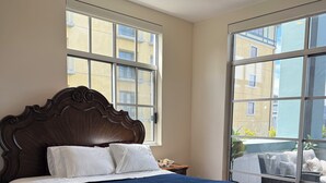 Un dormitorio con una cama grande, una mesita de noche, un ventanal y vistas al exterior.