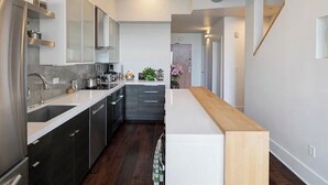 Una cocina moderna con armarios oscuros, una encimera blanca y una isla de madera.