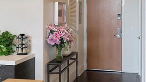 Un pasillo con una puerta de madera, una pequeña mesa con un florero y un cuadro colgado en la pared.