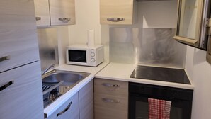 A modern kitchen with stainless steel appliances, a microwave, a dishwasher, and wooden cabinets. - Spacious studio in residence with swimming pool close to all amenities (Mougins)