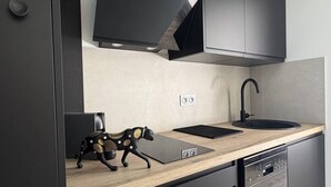 A modern kitchen with a wooden countertop, black appliances, and a unique decorative piece resembling a cow. - Le Jardin d'Eden 104 - Suite Junior Luxe - 2 people (AGDE)
