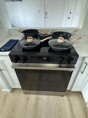 A kitchen with a stove, oven, and various pots and pans.