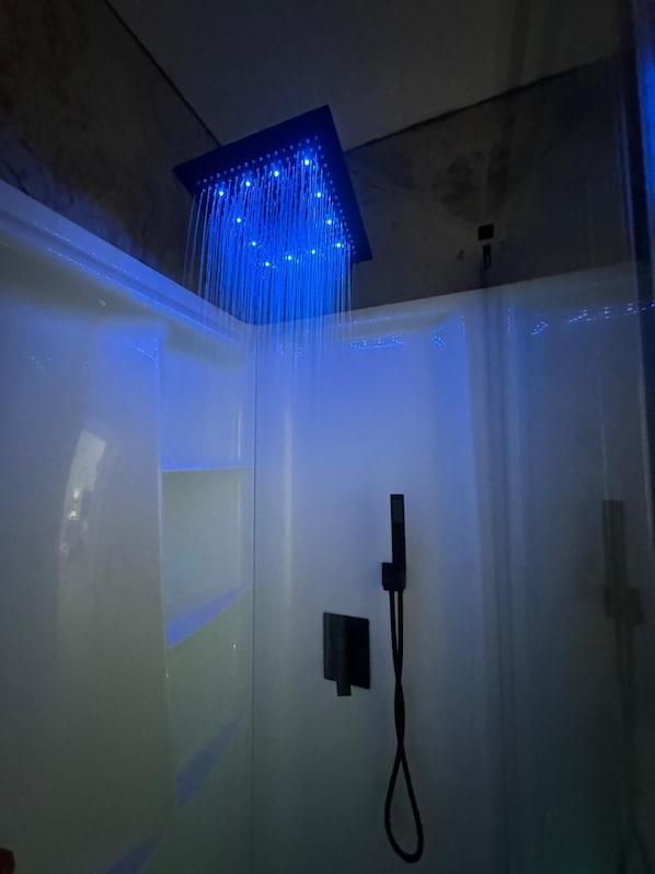 A shower with a square ceiling panel and blue LED lights.