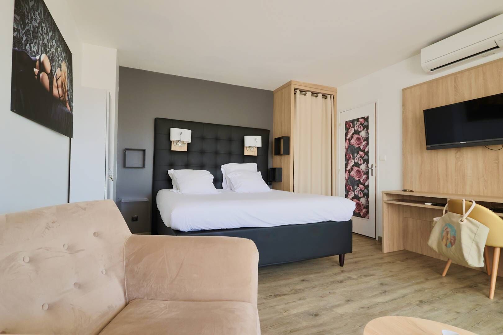 A hotel room with a bed, a TV, a desk, and a couch.