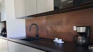 Eine moderne Küche mit Edelstahl-Schränken, einer schwarzen Arbeitsplatte, einer Bosch-Mikrowelle und einer Kaffeemaschine.
