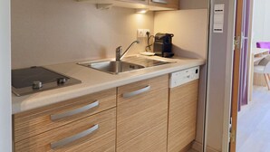 Una cocina compacta con armarios de madera, lavavajillas integrado y cafetera.