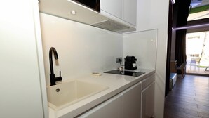 Una cocina compacta con un lavamanos, una cafetera y una ventana con vistas a un patio.