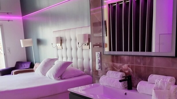 Habitación de hotel con cama, tocador con espejo y ventana con cortinas.