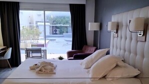 A hotel room with a large bed, a chair, a table, and a view of the outside. - Le Jardin d'Eden 113 - Suite Junior Premium - 2 people (AGDE)