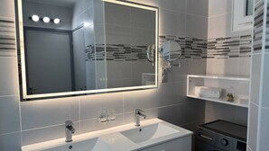 A modern bathroom with a large mirror, two sinks, a towel rack, and a washing machine. - Le Jardin d'Eden JE135 - Suite Junior Luxe with garage - 2 people (AGDE)