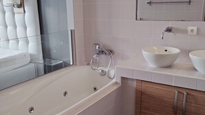 Een moderne badkamer met een vrijstaand bad, een wastafel en een spiegel boven het aanrecht.