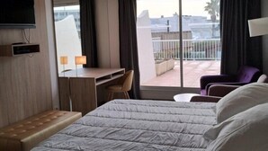 Hotelkamer met een bed, een bureau, een stoel, een televisie en een balkon met uitzicht.