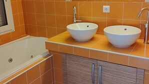 Un baño con dos lavabos, una bañera y un espejo.