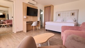 Una habitación de hotel con cama, escritorio, televisor, silla y sofá.