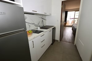 Een kleine keuken met een koelkast, een spoelbak en een vaatwasser.