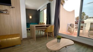 Une chambre d’hôtel moderne avec un bureau en bois, une table ronde, un canapé et une grande fenêtre avec des rideaux.