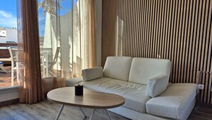 Un salon moderne avec un canapé, une table basse ronde et une grande fenêtre avec des rideaux.