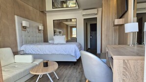 Une chambre d’hôtel moderne équipée d’un lit, d’un canapé, d’une table ronde et d’un bureau.