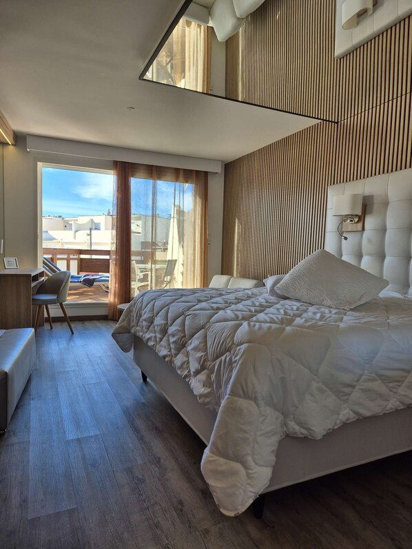 A modern bedroom with a large bed, a desk, and a view of the outside. - Le Jardin d'Eden - Suite Junior Luxe 139 with large terrace - 2 people (AGDE)