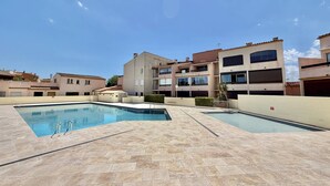 A swimming pool area with multiple pools and a building complex in the background. - CAP D'AGDE - MONT ST MARTIN // Réf 0314 (CAP D'AGDE)