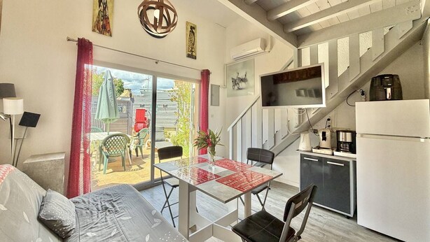 A modern kitchen with a refrigerator, stove, and sink. There is a dining area with a table and chairs, and a staircase leading to an upper level. - CAP D'AGDE - MONT ST MARTIN // Réf 0314 (CAP D'AGDE)