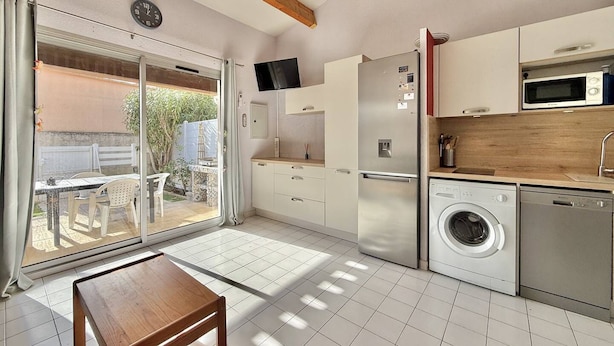 A modern kitchen with a built-in washing machine, a microwave, and a large window. - CAP D'AGDE - Richelieu // Réf 0309 (CAP D'AGDE)