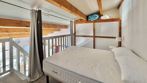 A bedroom with a bed, wooden ceiling beams, a view through a window, and a balcony. - CAP D'AGDE - Richelieu // Réf 0309 (CAP D'AGDE)