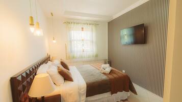 A hotel room with a bed, a TV mounted on the wall, and a window with curtains.