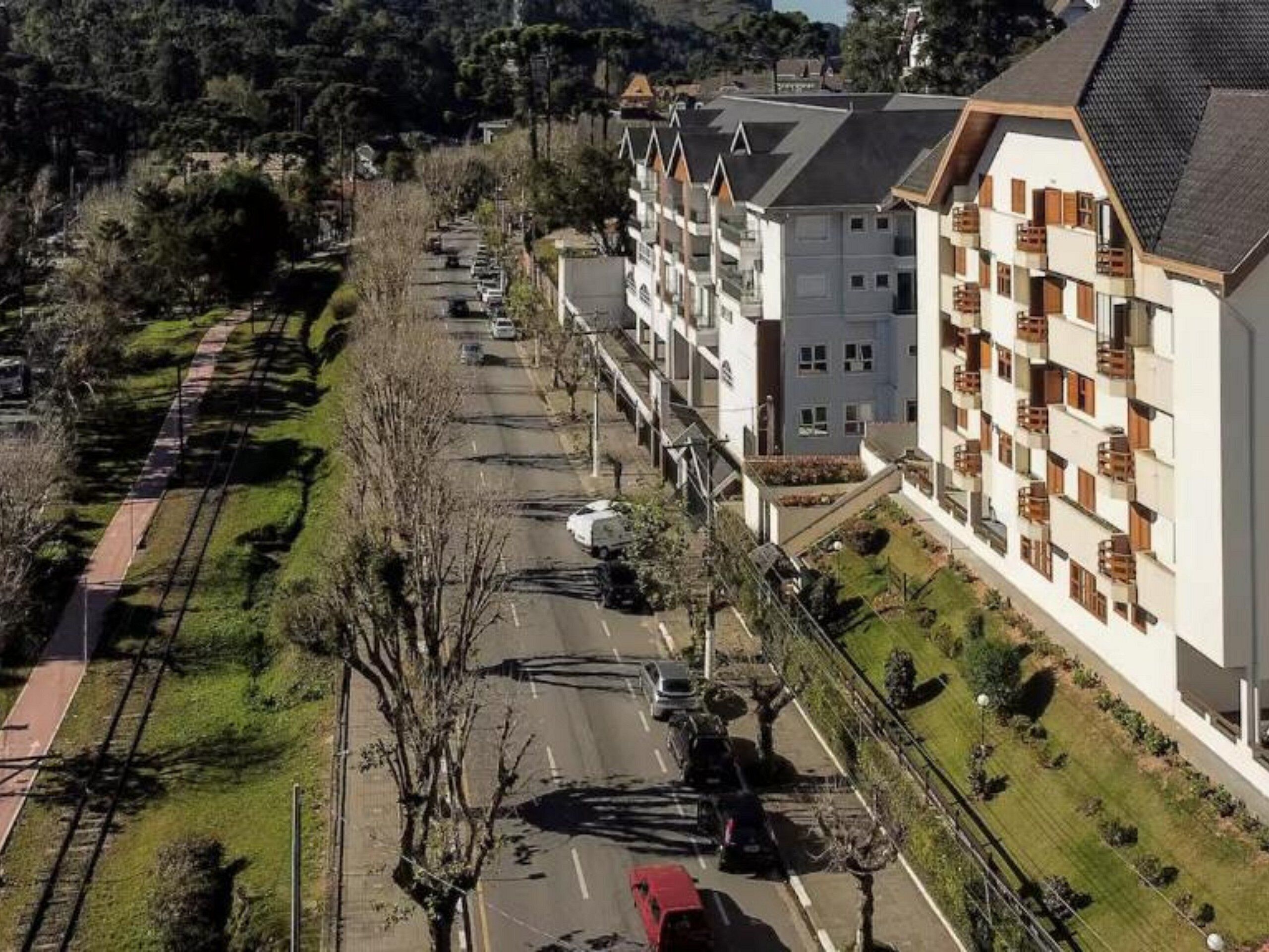 Un immeuble résidentiel à plusieurs étages, doté de balcons, d’un parking et situé à proximité d’une voie ferrée.