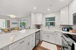 A modern kitchen with white cabinetry, a marble countertop, and a built-in oven. - BG Beach Club 3E | 3BR/2BA Boca Grande Condo (Boca Grande)