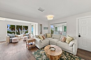 A spacious living room with a large sectional sofa, a round coffee table, and a view of the outdoors through large windows. - BG Beach Club 3E | 3BR/2BA Boca Grande Condo (Boca Grande)
