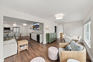 A spacious living area with a dining table, seating, and a kitchen in the background. - BG Beach Club 3E | 3BR/2BA Boca Grande Condo (Boca Grande)