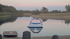 Une terrasse au bord du lac, avec des fauteuils Adirondack, une table ronde et un bateau.