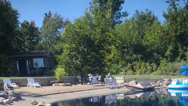Une piscine aux eaux cristallines, entourée de rochers, avec des chaises longues et un bâtiment en arrière-plan.