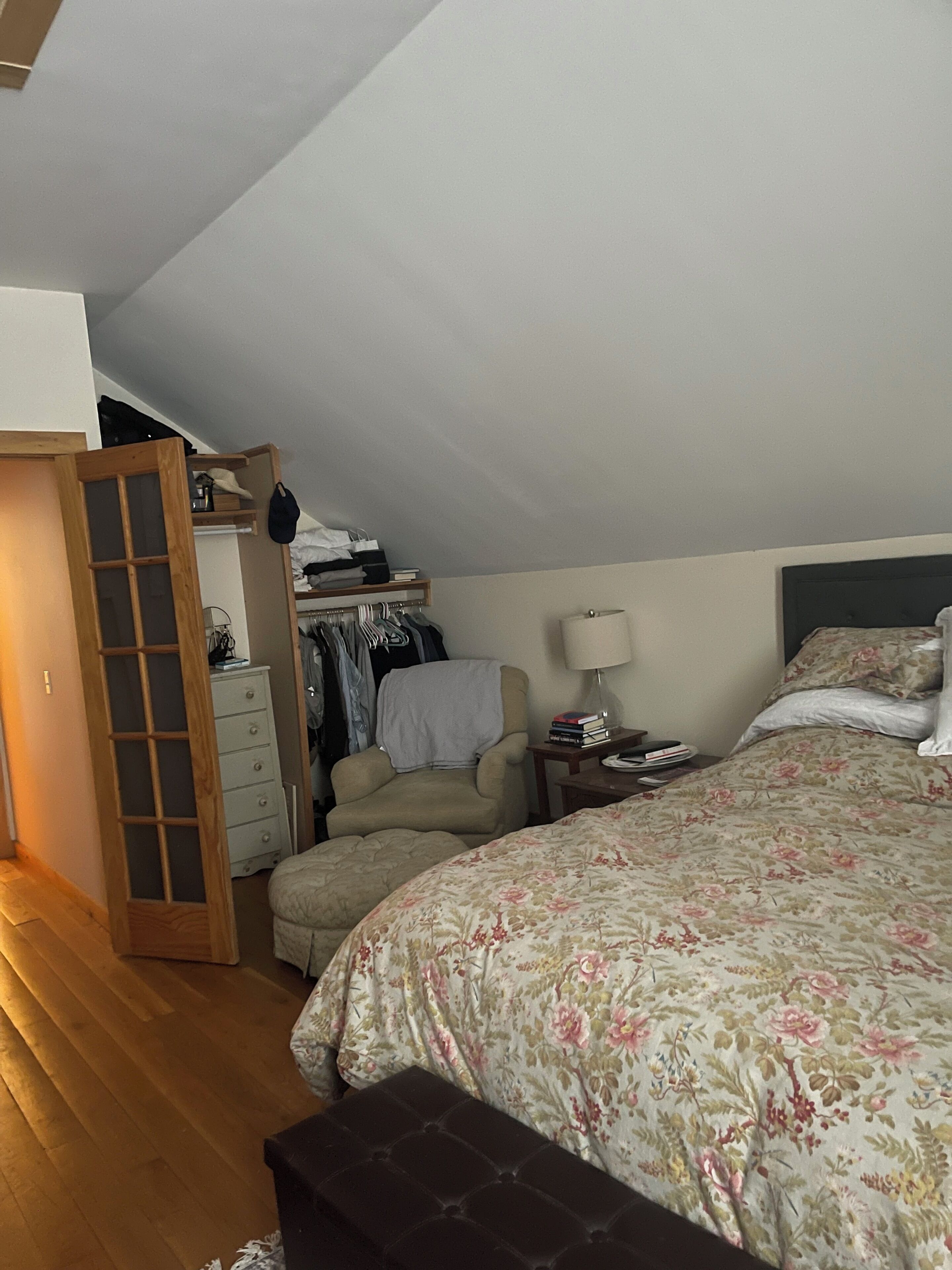 A bedroom with a bed, a chair, a dresser, and a closet.