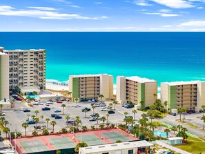 Ein Hochhaus-Hotel mit mehreren Etagen, einem Parkplatz und Blick auf den Strand.