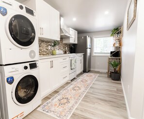 A compact kitchen with built-in appliances, a window, and a decorative rug. - 1BR Modern Loft in Windsor West by the bridge (Windsor)