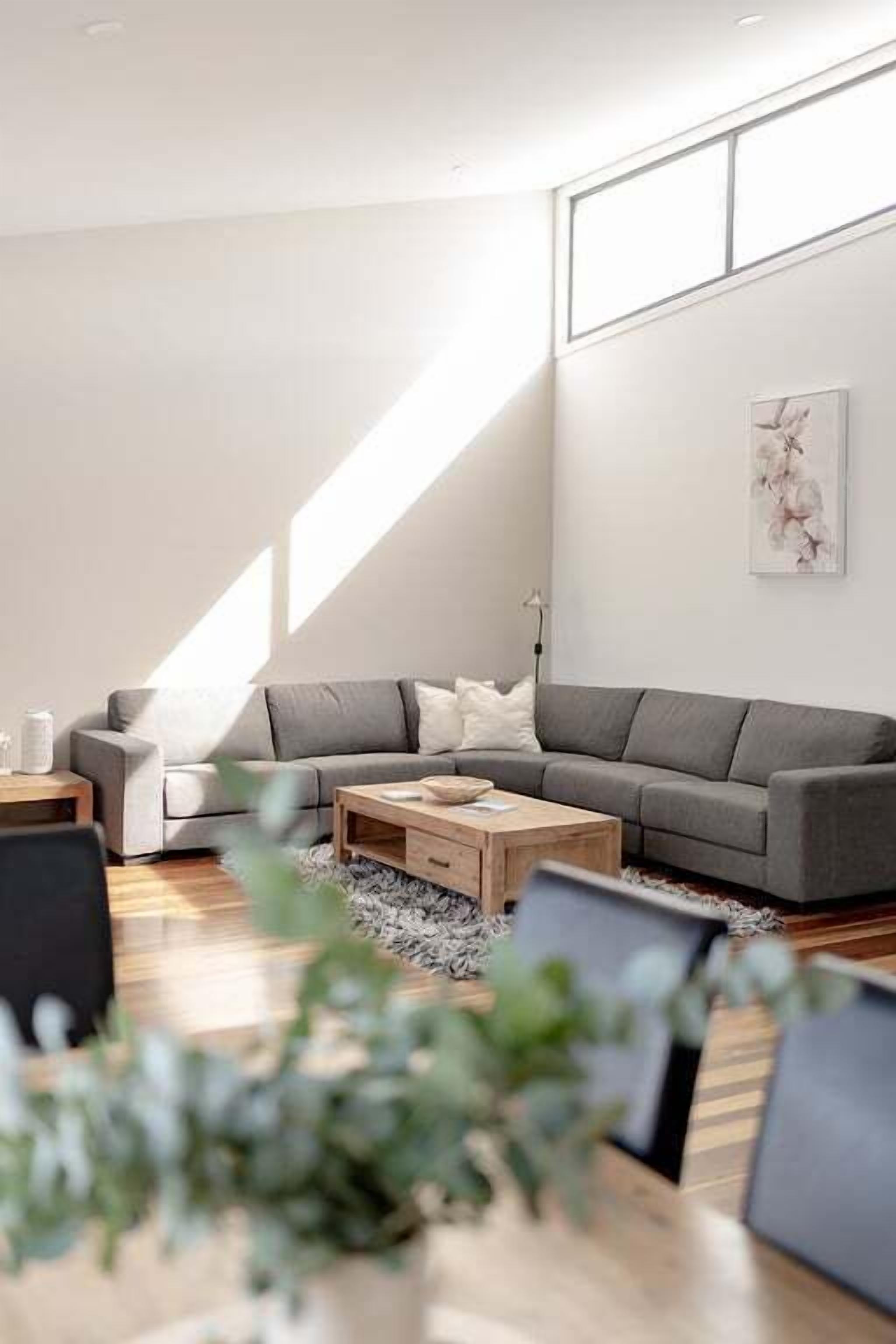 Un soggiorno moderno con un divano modulare grigio, un tavolino in legno e un piccolo tavolino laterale.